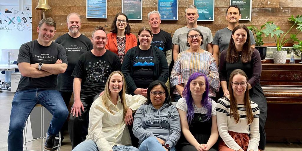 The Tourwriter team together in the Wellington office in front of the company values wall