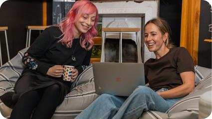 Two young professional women looking at a laptop while sitting on a beanbag