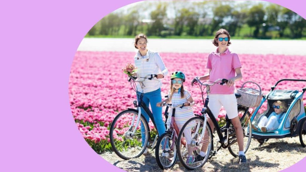 A family of travellers biking around pink tulips. 
