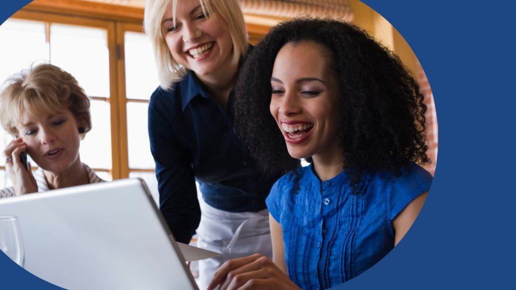 Two travel designers using a computer with tour operator software to complete an itinerary. A third travel designer is on the phone.