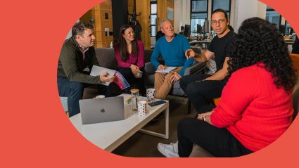 Tourwriter team in havign a meeting with a red background