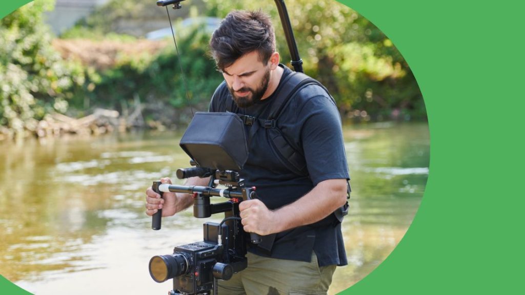 A cameraman filming on location at a river.