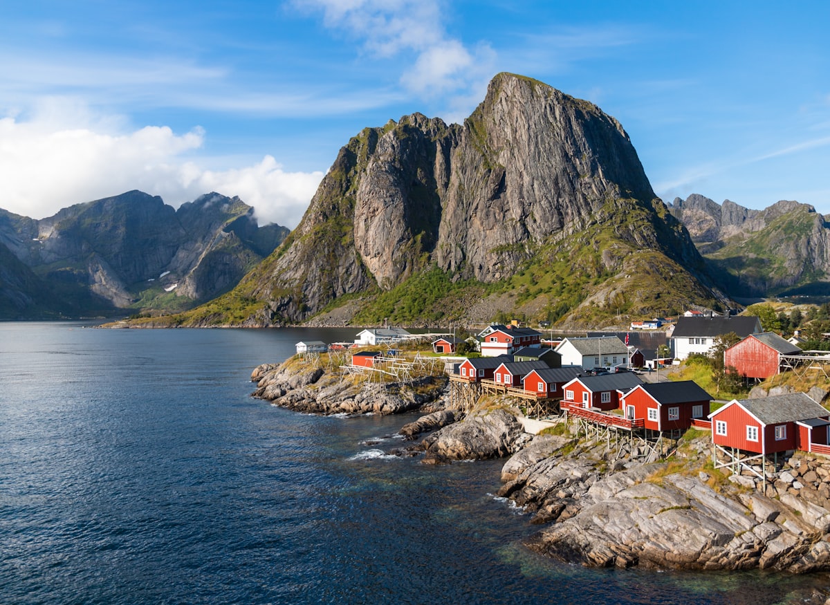Traditional red houses along the Lofoten archipelago waterfront, Norway, with dramatic mountain peaks behind