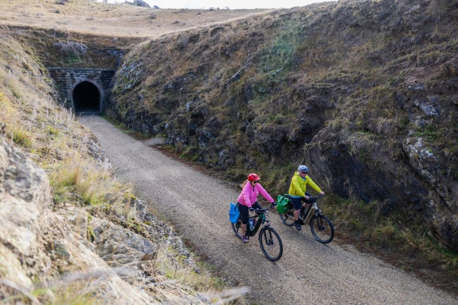 Cyclists emerging from a tunnel on the Otago Central Rail Trail with Bike It Now, Central Otago, New Zealand