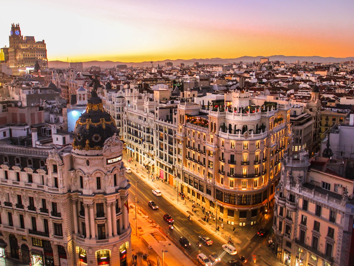 Aerial view of Gran Vía Madrid at sunset, traffic flowing between tall buildings, Spain city travel