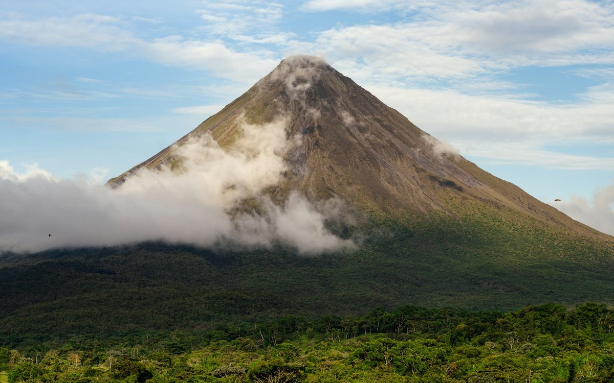 Arenal volcano rising above rainforest canopy in Costa Rica, a region Huellas e-travel designs itineraries for