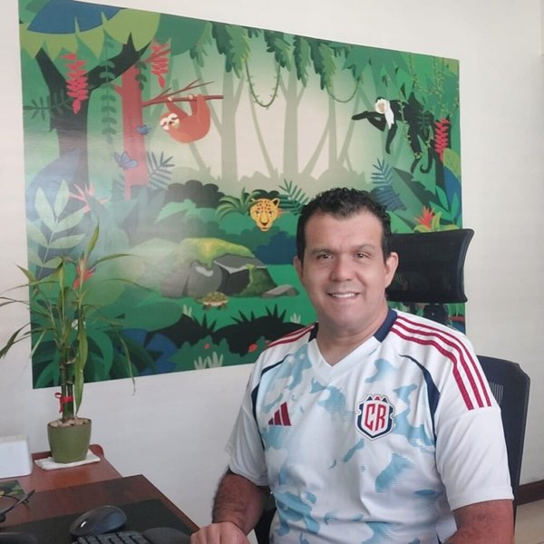 Mauricio Esquivel, founder of Huellas e-travel, smiling at his desk in Costa Rica